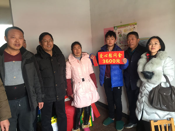 商會會長熊桂祥（左二）、監(jiān)事會主席李榮杰（右二）、秘書長徐敏（右一）和萬盛合作社總經(jīng)理王喜本（左一）帶著慰問團(tuán)正在慰問馬彩平母子（圖中），并與他們合影留念