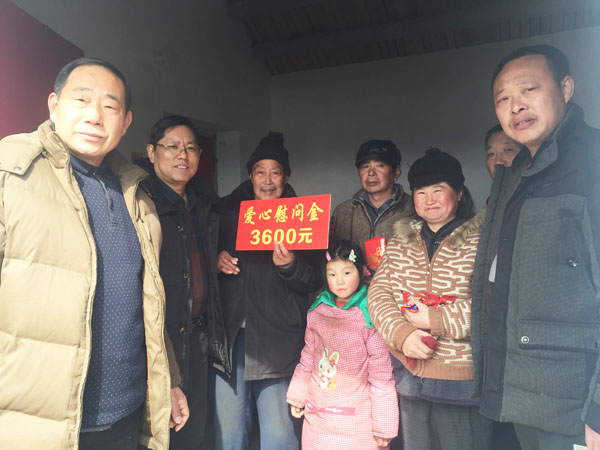 商會愛心尉問團(tuán)正在慰問張澤家全家（圖中），并與他們合影留念